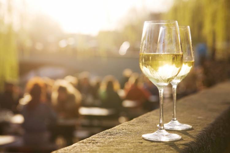 two glasses of white wine sitting on ledge outside